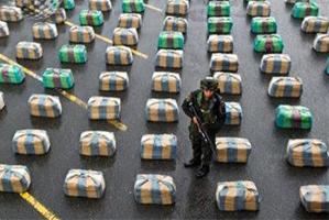 A Colombian police officer stands guard next to packages with 7.7 tons of seized marijuana. Photo / AFP