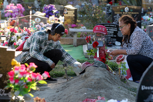 Lachan Kelly-Tumarae's grandmother Narina Tumarae (right) and cousin Gilbert Tumarae lay tributes at his grave, two years after the teenager was fatally shot by police. Photo / Duncan Brown