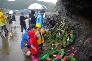Anzac Day visitors read the plaque at the base of Piha's Lion Rock. Photo / Supplied