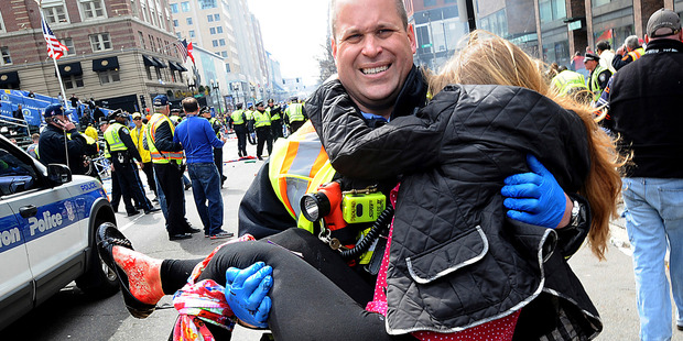 Boston Firefighter James Plourde carries an injured girl away from the scene. Rescuers immediately turned to a millennia-old medical device to save victims' lives - the tourniquet. Photo / AP