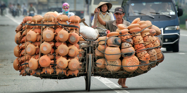 A Vietnamese man pushes a full load of clay pots along what was once the Ho Chi Minh trail, Vietnam. Photo / AP