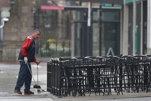 A man sweeps around the outdoor seating area on Boylston St in Boston as business owners prepare to reopen. Photo / AP