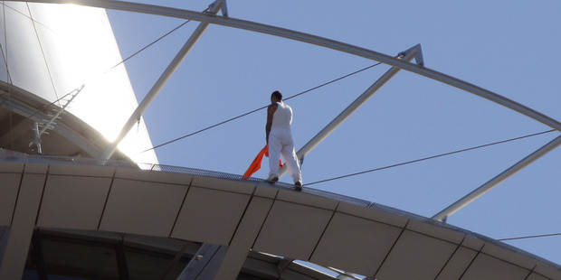 The man uses his jacket to balance on the side of the Sky Tower rim. Photo / Doug Sherring