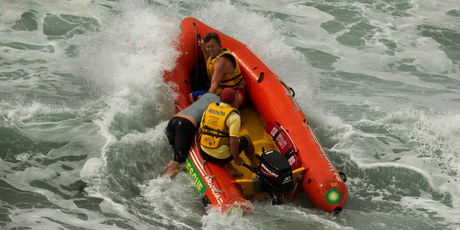 Lifeguards perform a rescue at Mt Maunganui's main beach yesterday after a large swell built up quickly, catching some surfers unawares. Photo / Alan Gibson.