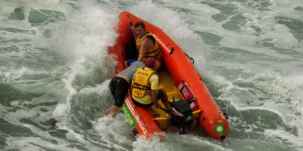 Lifeguards perform a rescue at Mt Maunganui's main beach yesterday after a large swell built up quickly, catching some surfers unawares. Photo / Alan Gibson.