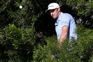 Dustin Johnson hits out of the woods during the final round of the Tournament of Champions. Photo / AP
