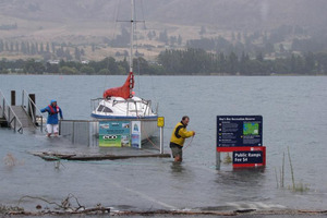 Wanaka holiday-makers Brett Gawn and his wife, Fay Paterson, wade through the rising water to remove their boat from Lake Wanaka. Photo / Lucy Ibbotson