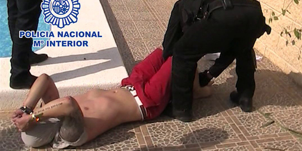 British fugitive Andrew Moran is arrested by police next to a swimming pool in Spain. Photo / AP