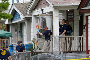 Members of the FBI evidence response team carry out the front screen door from the house where three women were held captive, in Cleveland. Photo / AP