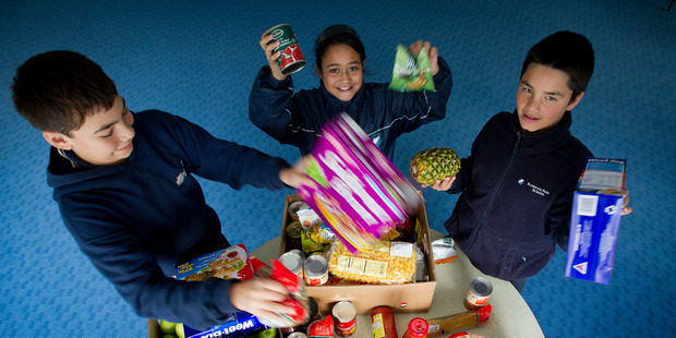 Andrew Leef, 13, Hineataarau Kohu, 10, and Damon Maireroa help to pack a food parcel at Randwick Park School in Manurewa as part of its food bank programme. Photo / Sarah Ivey