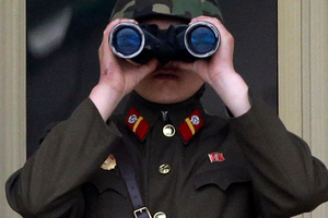 A North Korean soldier looks at the south side through a pair of binoculars at the border village of Panmunjom.Photo / AP