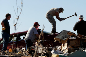 James Pitts uses a sledge hammer to try to force open a friend's trunk in a tornado-ravaged car as residents sort through their tornado-ravaged homes. Photo / AP