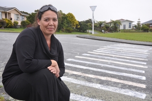 Stirling Drive resident Line Low next to the 'pedestrian crossing' that popped up at Arnott Heights, Greymouth, yesterday. It has since been washed off by contractors. Photo / Greymouth Star