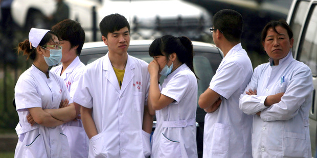 Medical staff wait near a poultry processing plant that was engulfed by a fire in Mishazi, Jilin, in China. Photo / AP