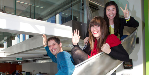 Trade Me staff members (from left) Pete Soldini, Hannah Martin and Kitty Song on the slide between the first and ground floors of their Wellington office. Photo / Mark Mitchell