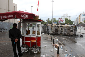 A bagel vendor stands behind a destroyed mini bus the Taksim Square in Istanbul. Photo / AP