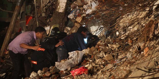 Rescue workers look for trapped people after a residential building collapsed in Mahim, central Mumbai. Photo / AP