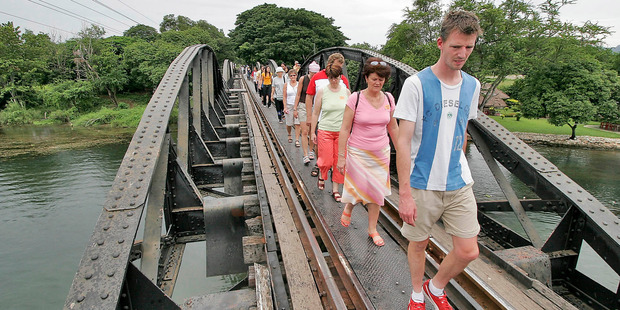 Tourists cross the bridge on the River Kwai in Kanchanaburi. Below: Peter Feeney and his children visit the Death Railway.