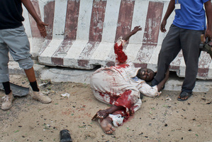 A man who was wounded during an attack on the UN compound lies in the street waiting to be carried away to seek medical attention, in Mogadishu, Somalia. Photo / AP