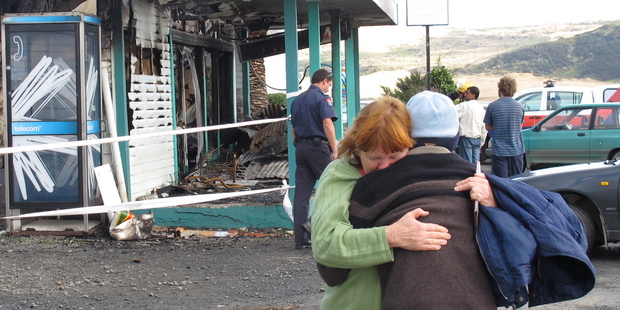 A customer comforts a member of the shop owner's family after Opononi's Four Square was razed by fire. Photo / APN