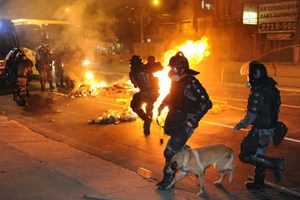 Riot policemen try to extinguish a fire barricade set up by demonstrators in downtown Niteroi, near Rio de Janeiro, Brazil. Photo / AFP
