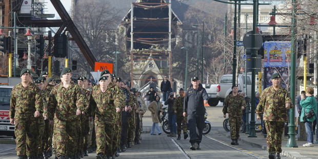 The ruins of Christchurch Cathedral form the backdrop as New Zealand Defence Force personnel march into Worcester Boulevard for a ceremony marking the end of the Red Zone. Photo / SNPA