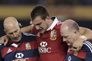 British and Irish Lions' captain Sam Warburton, center, is helped off the field by team trainers while playing Australia in their rugby union test match. Photo / AP