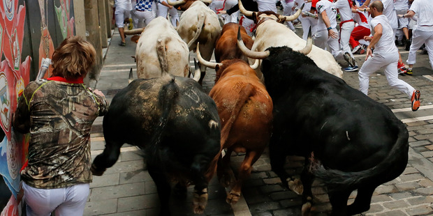 Revellers run with El Pilar's ranch fighting bulls at Curva Estafeta during the seventh day of the San Fermin Running Of The Bulls festival. Photo / Getty Images