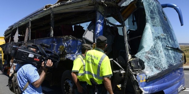 Members of Spain's Guardia Civil inspect a damaged bus after it crashed on the N-403 road, near Avila, killing nine. Photo / AFP