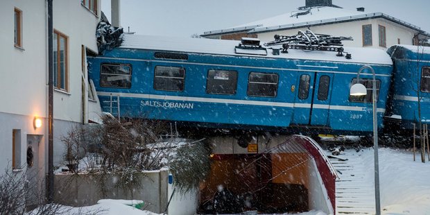 The derailed train that hangs on the edge of the track after it crashed into the side of a residential building in Saltsjobaden outside Stockholm. Photo / AP