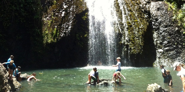 Children play in the water at the foot of the Kitekite Falls. Photo / Supplied