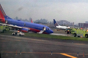 A Southwest Airlines plane whose nose gear collapsed as it touched down on the runway is surrounded by emergency vehicles at LaGuardia Airport in New York. Photo / Jared Rosenstein