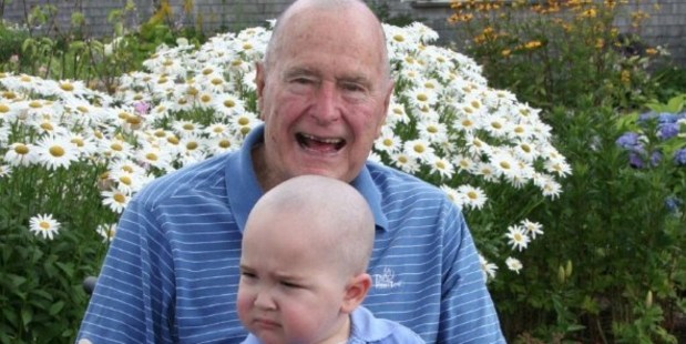 Former US President George H. W. Bush poses on Walker's Point, Kennebunkport, with his head shaved to show support for two year-old Patrick. Photo / AFP