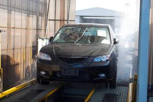 A vehicle is driven through a 'de-con' cleaning machine during the importation process.