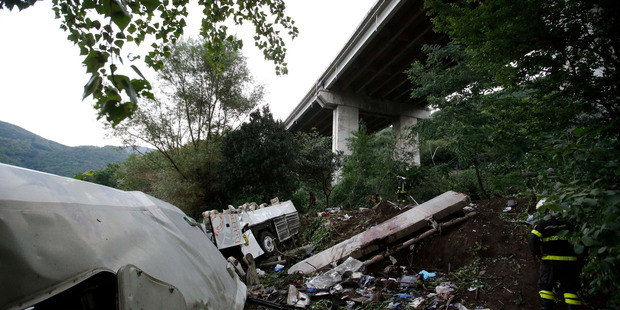 A firefighter stands near the wreckage of a bus following the crash near Avellino in southern Italy. Photo / AP