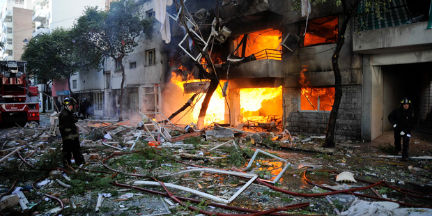 Firemen stand in debris caused by a gas explosion that has severely damaged a multi-story apartment building in Rosario, Argentina. Photo / AP