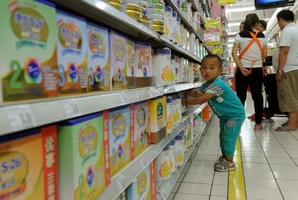 A toddler plays in the imported baby products section while his parents purchase baby products in a Beijing supermarket. Photo / AFP