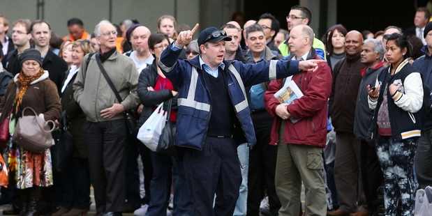 A worker directs commuters to alternative transport after train services were cancelled. Photo / Getty Images