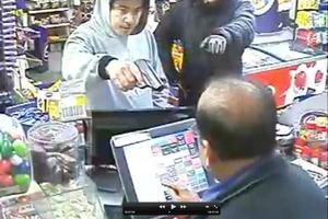 The robbers, one armed, threaten shopkeeper Ravi Khattar.