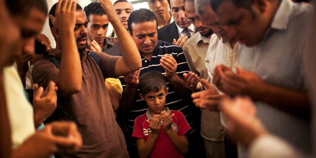 A grandson of Muslim Brotherhood spiritual leader Mohammed Badie prays for his father, Ammar Badie, killed by security forces in clashes in Ramses Square, Cairo. Photo / AP