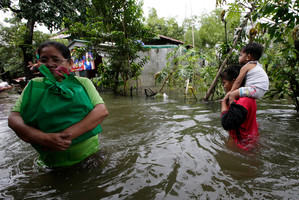 Residents wade through floodwaters after receiving relief goods from a non-government organization. Photo / AP