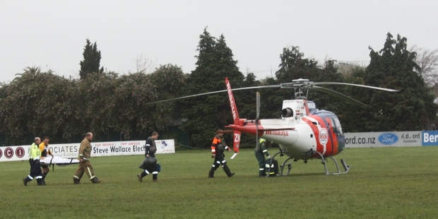 Dannevirke Volunteer Fire Brigade members and referee James Kendrick carry the under-13 rugby player to the Palmerston North Rescue Helicopter at Rugby Park on Sunday afternoon. Photo / Christine McKay
