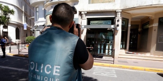 A forensic policeman takes a picture as he investigates outside the Kronometry shop on July 31, 2013, after two armed men held up a store selling luxury watches in the French Riviera town of Cannes, t