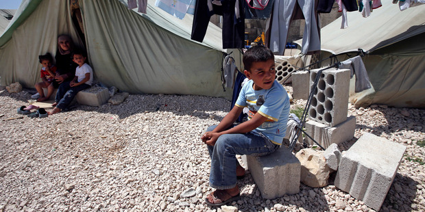 A Syrian refugee boy sits outside his tent next to his family at a temporary refugee camp.Photo / AP