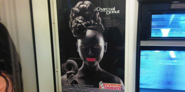 An advertisement poster of a smiling woman with bright pink lips in blackface makeup holding a doughnut is seen on a Skytrain, a commuter train in Bangkok, Thailand. Photo / AP