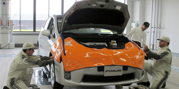 Mechanics work on Prius at a newly completed Toyota's service center in Tajimi, central Japan, Monday, July 22, 2013.