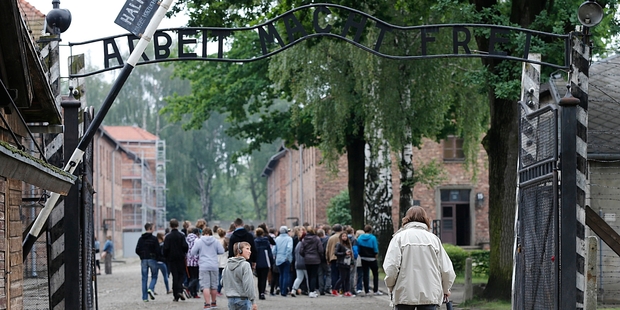 Tourists wander under the famous Auschwitz gate in Poland. Visitors to the former Nazi death camp are able to explore the grounds and learn about its history. Photo / AP