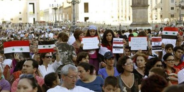 People hold Syrian flags and signs against a possible attack to Syria, prior to the start of a vigil for peace attended by Pope Francis in St. Peter's Square at the Vatican. Photo / AP
