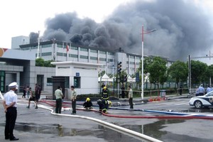 Emergency personnel at the scene as heavy smoke rises from the SK Hynix facility. Photo / AFP
