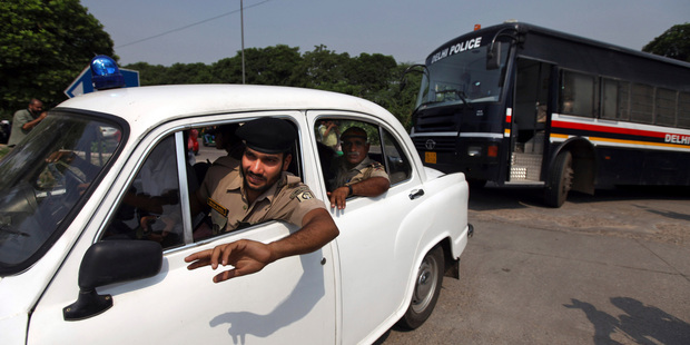 A policeman clears the way for a vehicle carrying four men convicted in the fatal gang rape of a young woman on a moving New Delhi bus. Photo / AP